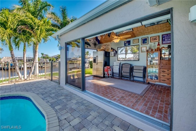 view of patio / terrace with a water view, ceiling fan, and a fenced in pool