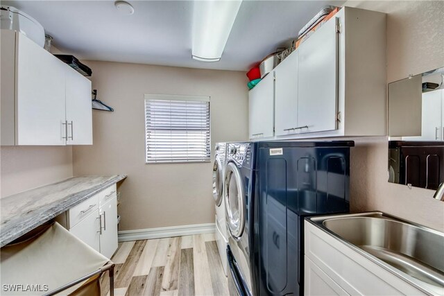 laundry area with cabinets, washing machine and dryer, light hardwood / wood-style flooring, and sink