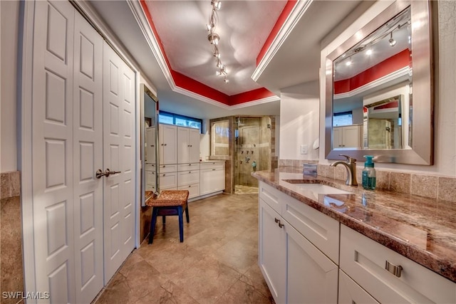 bathroom featuring vanity, a tray ceiling, crown molding, and a shower with shower door