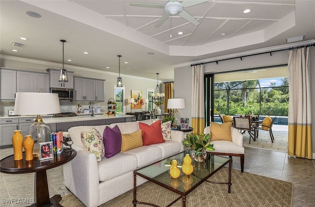 tiled living room featuring a raised ceiling, ceiling fan, and ornamental molding