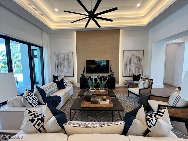 living room featuring a towering ceiling, wood-type flooring, and a tray ceiling