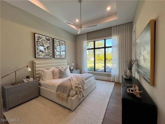 bedroom with wood-type flooring and a raised ceiling