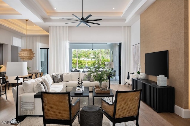 living area featuring a tray ceiling, light wood-type flooring, and a high ceiling