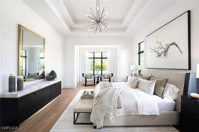 bedroom featuring a chandelier, a tray ceiling, and light wood finished floors