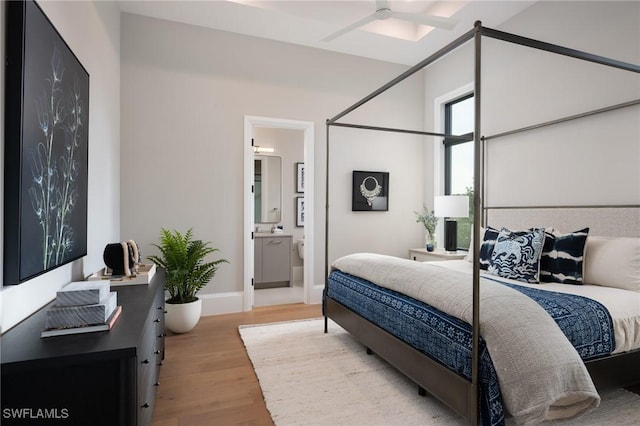 bedroom with connected bathroom, baseboards, and wood finished floors