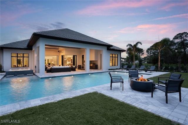 outdoor pool featuring a ceiling fan, a patio area, an outdoor living space with a fire pit, and a lawn