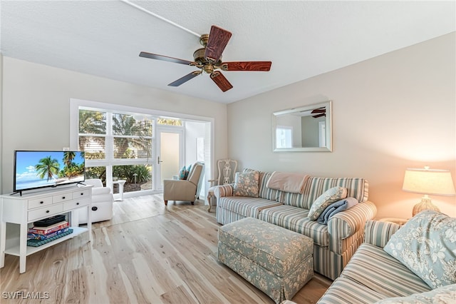 living room featuring a textured ceiling, light wood-type flooring, and ceiling fan