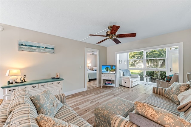 living room featuring a textured ceiling, ceiling fan, and light hardwood / wood-style floors