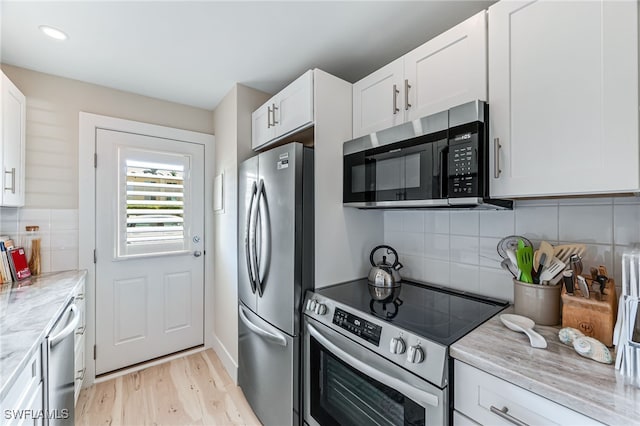 kitchen with light stone counters, light hardwood / wood-style flooring, backsplash, white cabinetry, and appliances with stainless steel finishes