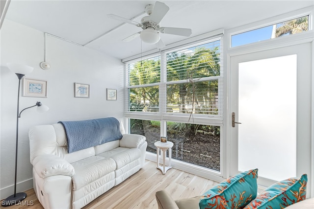 living room with a wall of windows, light wood-type flooring, and ceiling fan