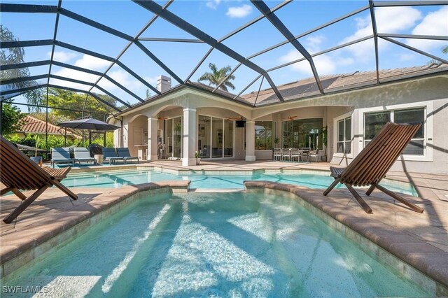 view of pool with ceiling fan, outdoor lounge area, glass enclosure, and a patio