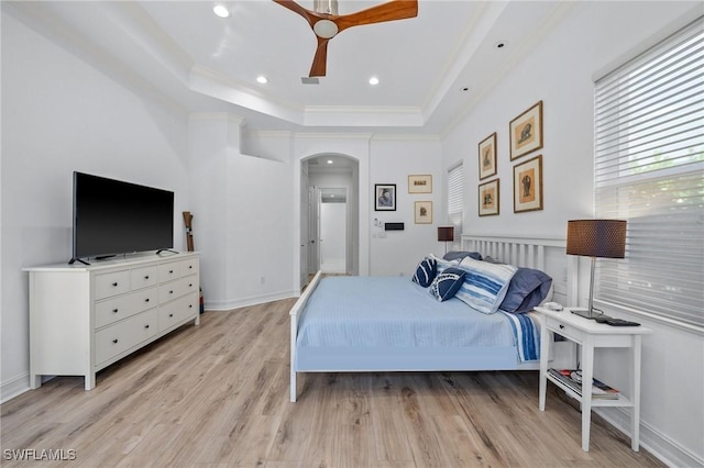 bedroom featuring crown molding, a tray ceiling, and light hardwood / wood-style flooring