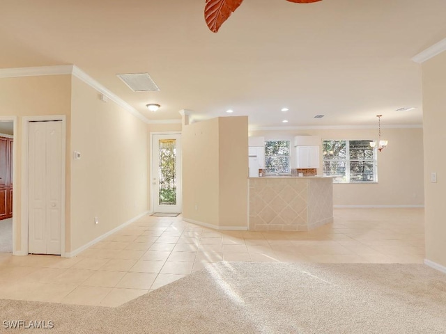 spare room with crown molding, a chandelier, light tile patterned floors, and a healthy amount of sunlight