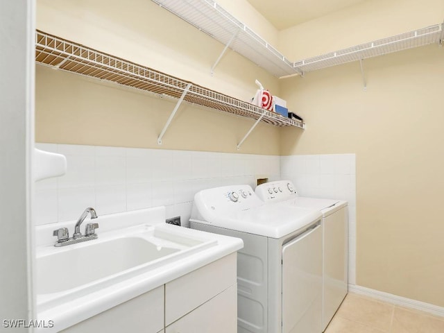 laundry area with sink, washing machine and clothes dryer, and light tile patterned floors