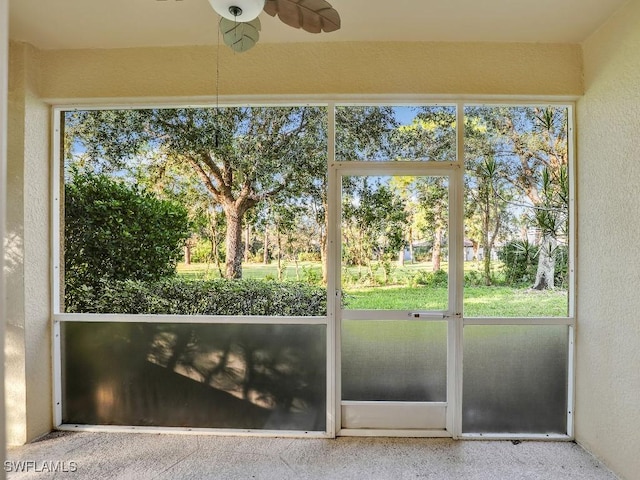 unfurnished sunroom with ceiling fan