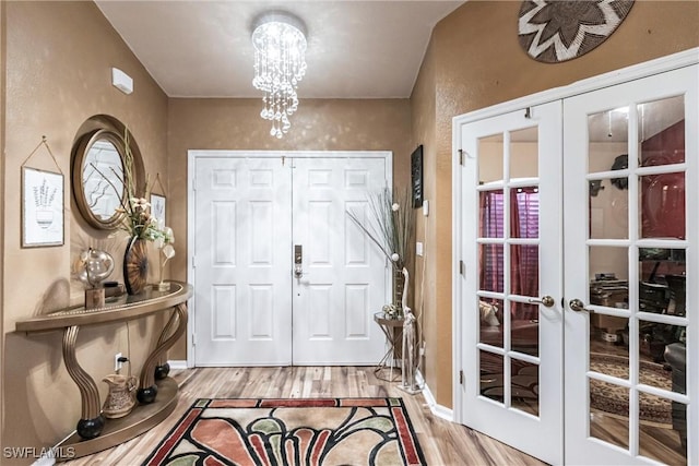 foyer featuring french doors, hardwood / wood-style floors, and a notable chandelier