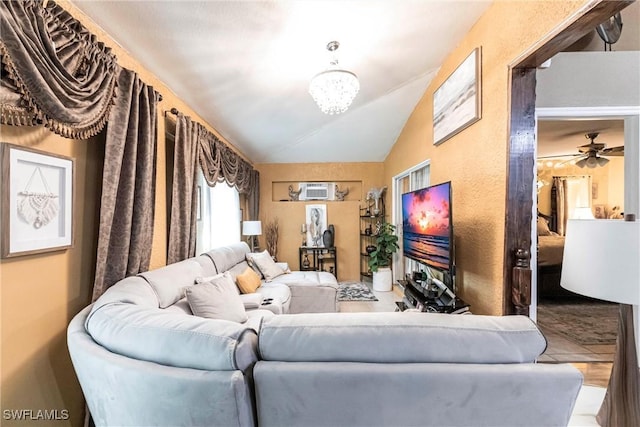 living room with ceiling fan with notable chandelier and vaulted ceiling