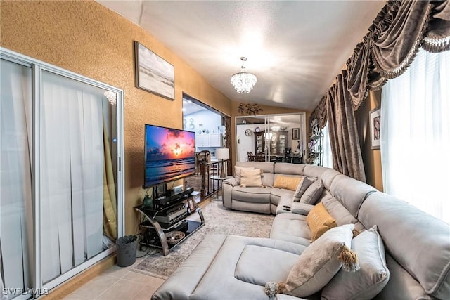 living room with a notable chandelier, light tile patterned flooring, and lofted ceiling