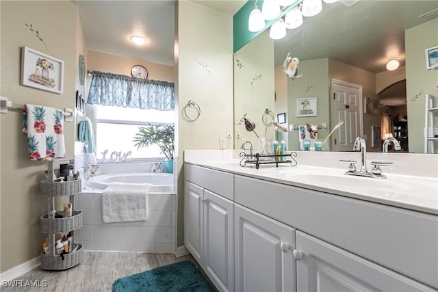 bathroom featuring hardwood / wood-style floors, vanity, and tiled bath