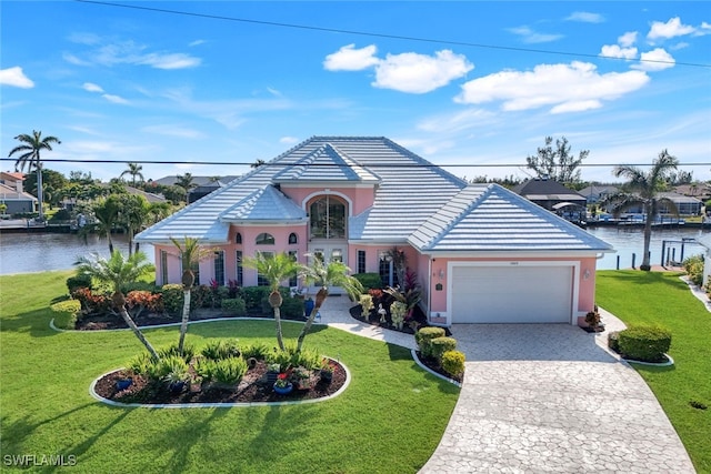 view of front of property featuring a front yard, a garage, and a water view