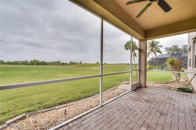 unfurnished sunroom featuring ceiling fan