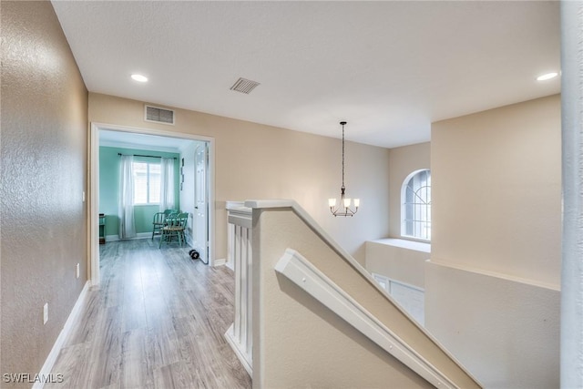 corridor with a notable chandelier and light hardwood / wood-style floors