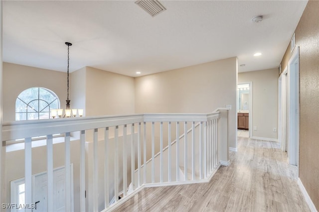 hallway featuring an inviting chandelier and light hardwood / wood-style flooring