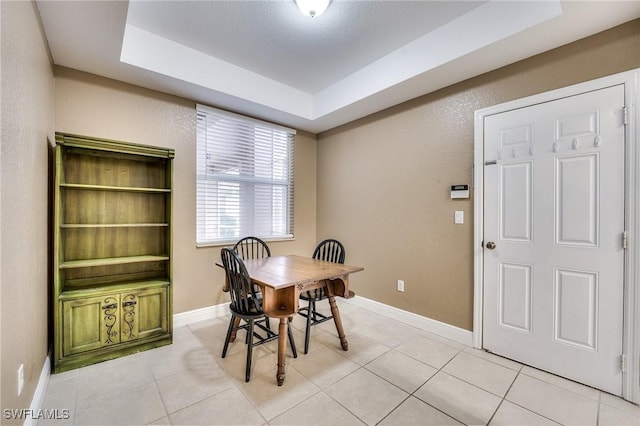 dining room with a raised ceiling and light tile patterned flooring