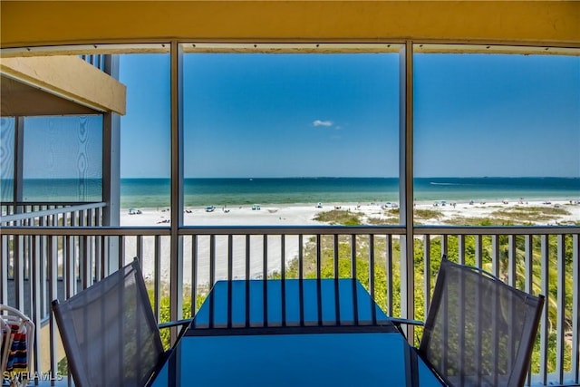 unfurnished sunroom featuring a water view and a view of the beach