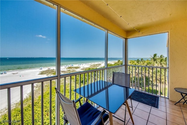 unfurnished sunroom with a water view, a wealth of natural light, and a view of the beach