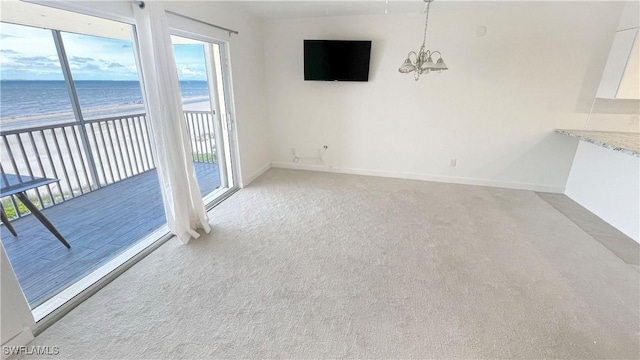 100 Estero Blvd Unit 434, Fort Myers Beach, FL 33931 - unfurnished living room with a chandelier, view of water and beach, light colored carpet, and baseboards