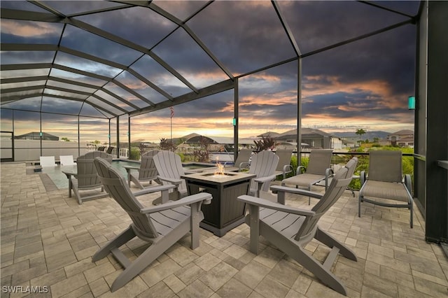 patio terrace at dusk featuring a lanai and a fire pit