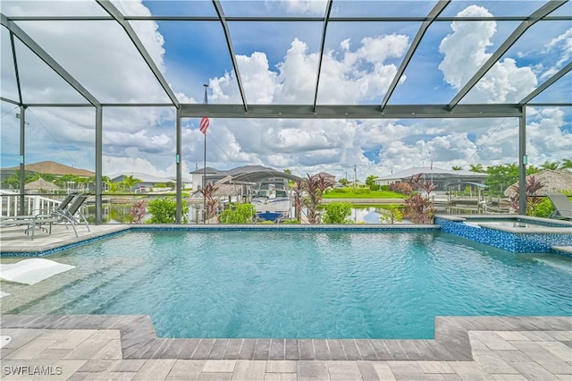 view of pool with an in ground hot tub, a water view, glass enclosure, and a patio area