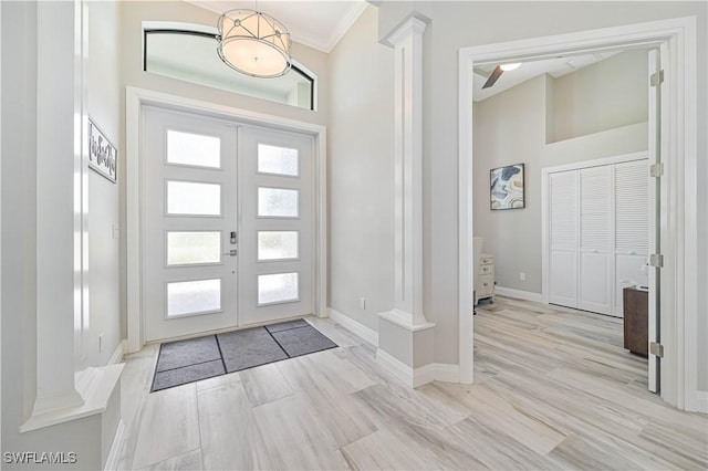 foyer featuring crown molding, light hardwood / wood-style floors, french doors, and ornate columns