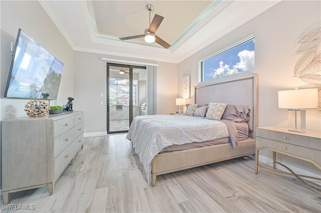 bedroom featuring crown molding, light hardwood / wood-style flooring, access to outside, a tray ceiling, and ceiling fan