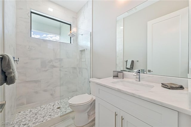 bathroom featuring hardwood / wood-style floors, vanity, a tile shower, and toilet