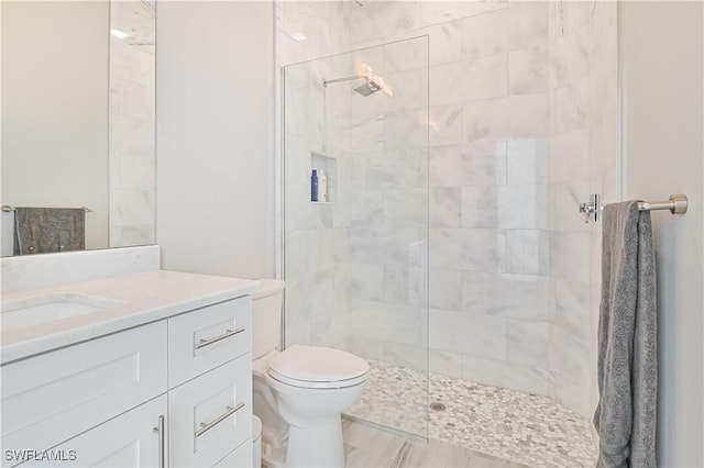 bathroom featuring tiled shower, vanity, and toilet