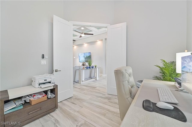 home office with beamed ceiling, coffered ceiling, ceiling fan, and light wood-type flooring