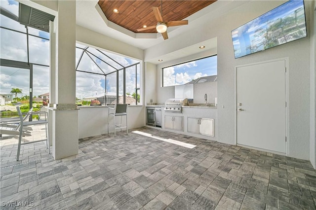 view of patio featuring a grill, glass enclosure, ceiling fan, and an outdoor kitchen