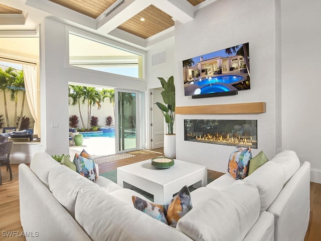 living room featuring coffered ceiling, wood-type flooring, wooden ceiling, ornamental molding, and beamed ceiling