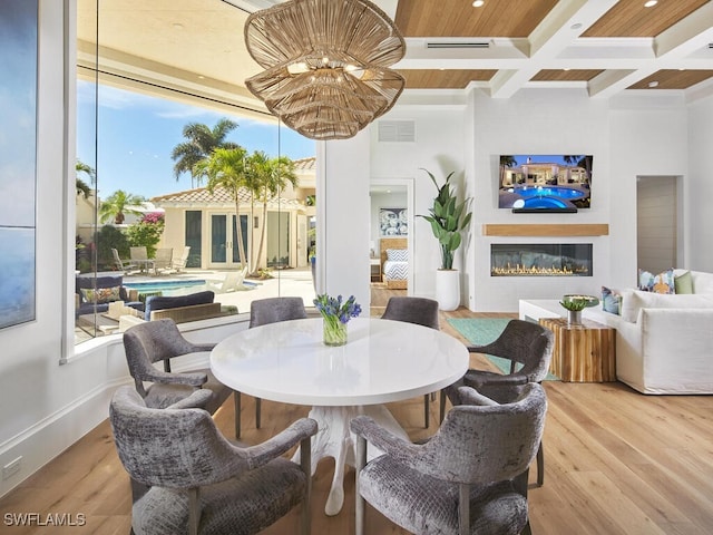 dining area featuring coffered ceiling, hardwood / wood-style flooring, and plenty of natural light