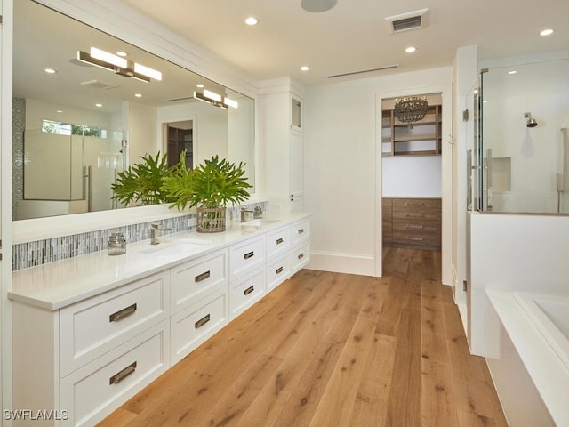 bathroom with vanity, hardwood / wood-style flooring, tasteful backsplash, and a shower with door