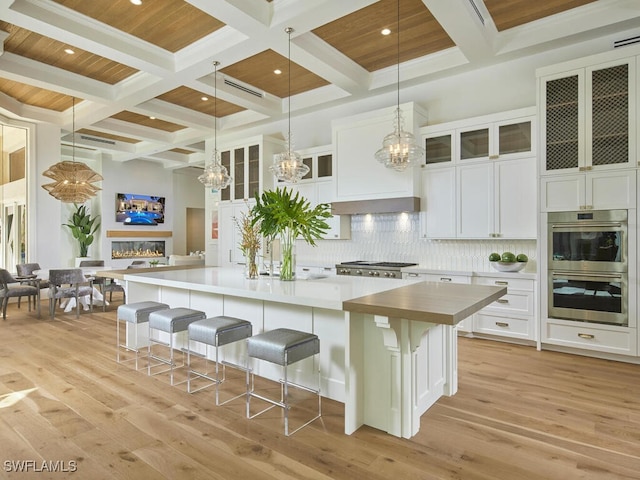 kitchen featuring white cabinetry, stainless steel appliances, a large island, and a kitchen bar