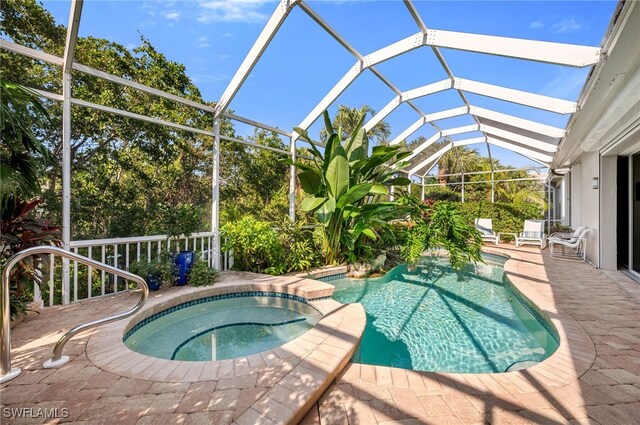 view of pool featuring glass enclosure, an in ground hot tub, and a patio