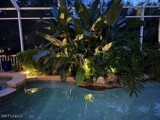 view of pool featuring glass enclosure and an in ground hot tub