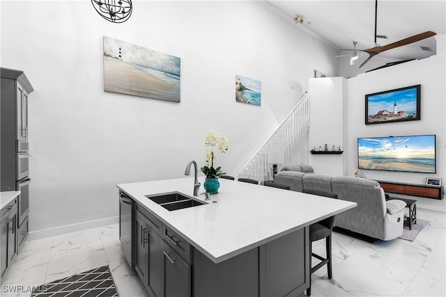 kitchen featuring dishwasher, a kitchen island with sink, sink, and gray cabinetry