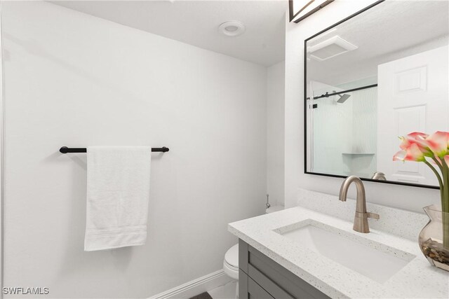 bathroom with a shower with door, vanity, and toilet