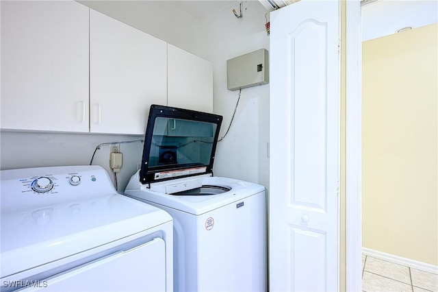 clothes washing area featuring light tile patterned floors, cabinets, and washer and dryer