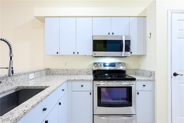 kitchen featuring light stone countertops, sink, white cabinetry, and appliances with stainless steel finishes