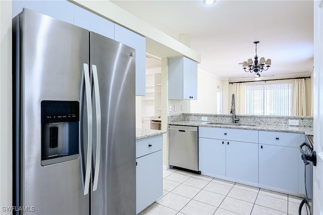 kitchen with appliances with stainless steel finishes, sink, light stone counters, a notable chandelier, and ornamental molding